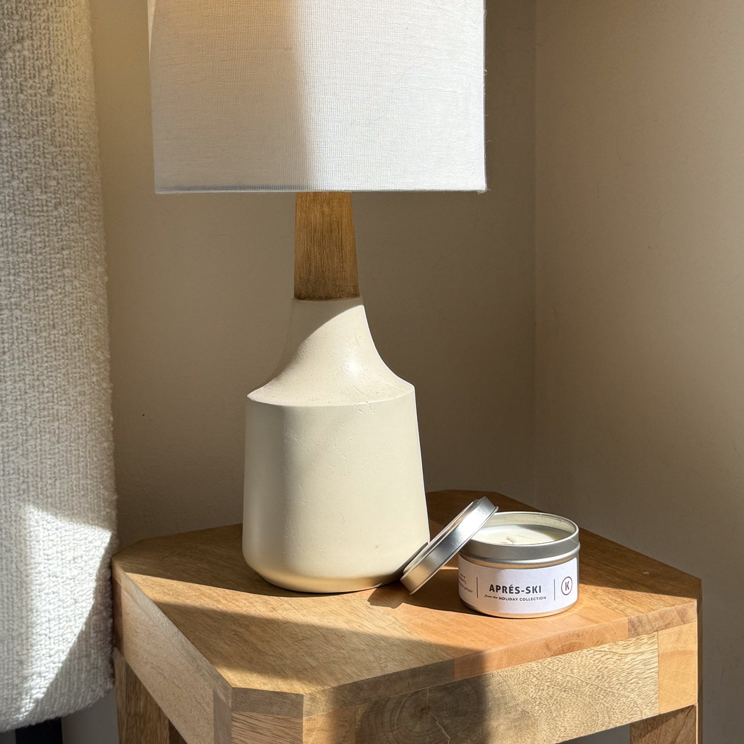 White ceramic lamp and candle on a wooden surface with a neutral background