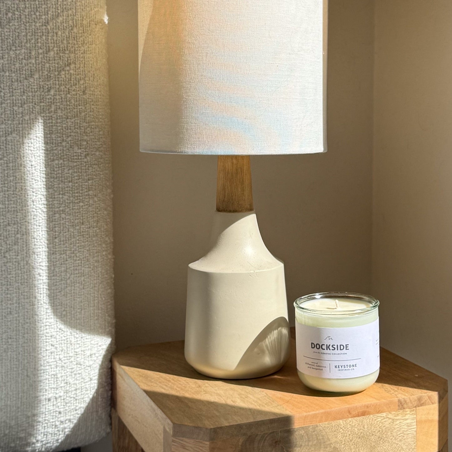 Candle labeled 'Dockside' next to a white lamp on a wooden surface.