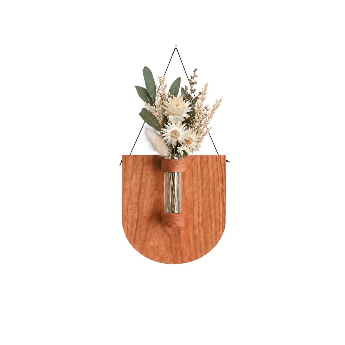 A wooden wall-mounted planter with a rounded shield shape and a clear glass vase, holding dried white flowers and greenery, hanging against a plain white wall.