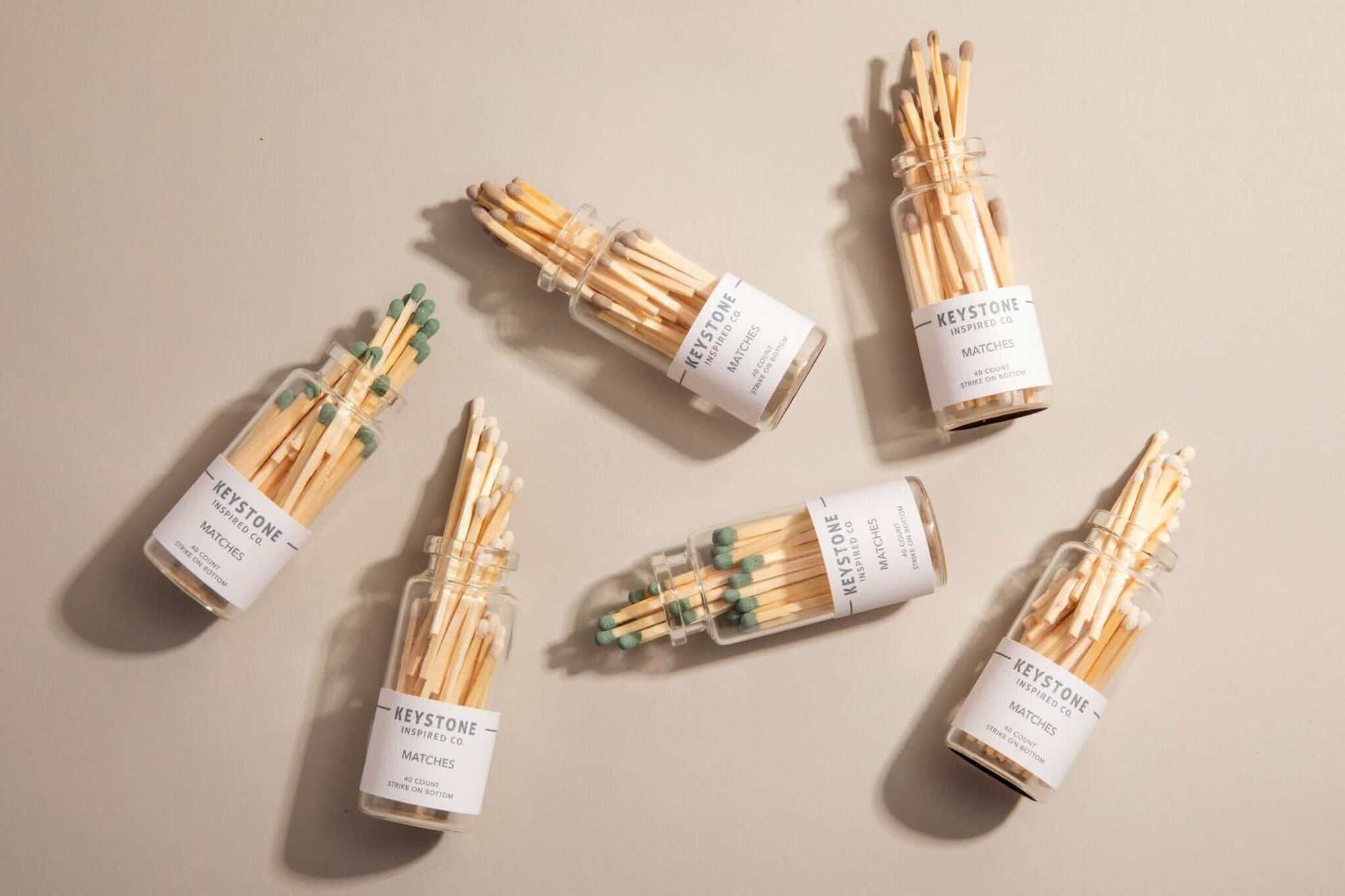 Multiple small jars of matches with labels on a beige background