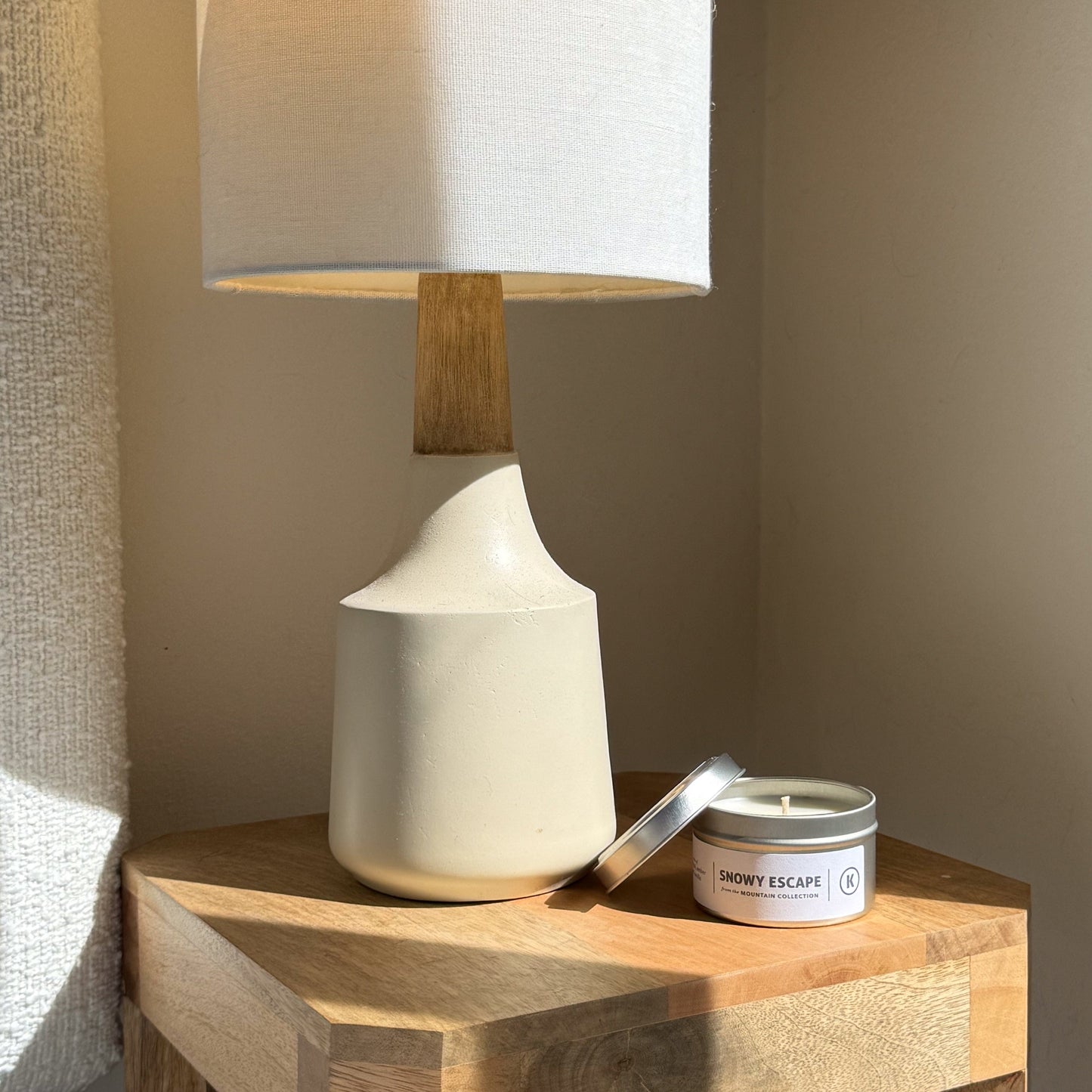 White ceramic lamp and candle on a wooden surface with a neutral background
