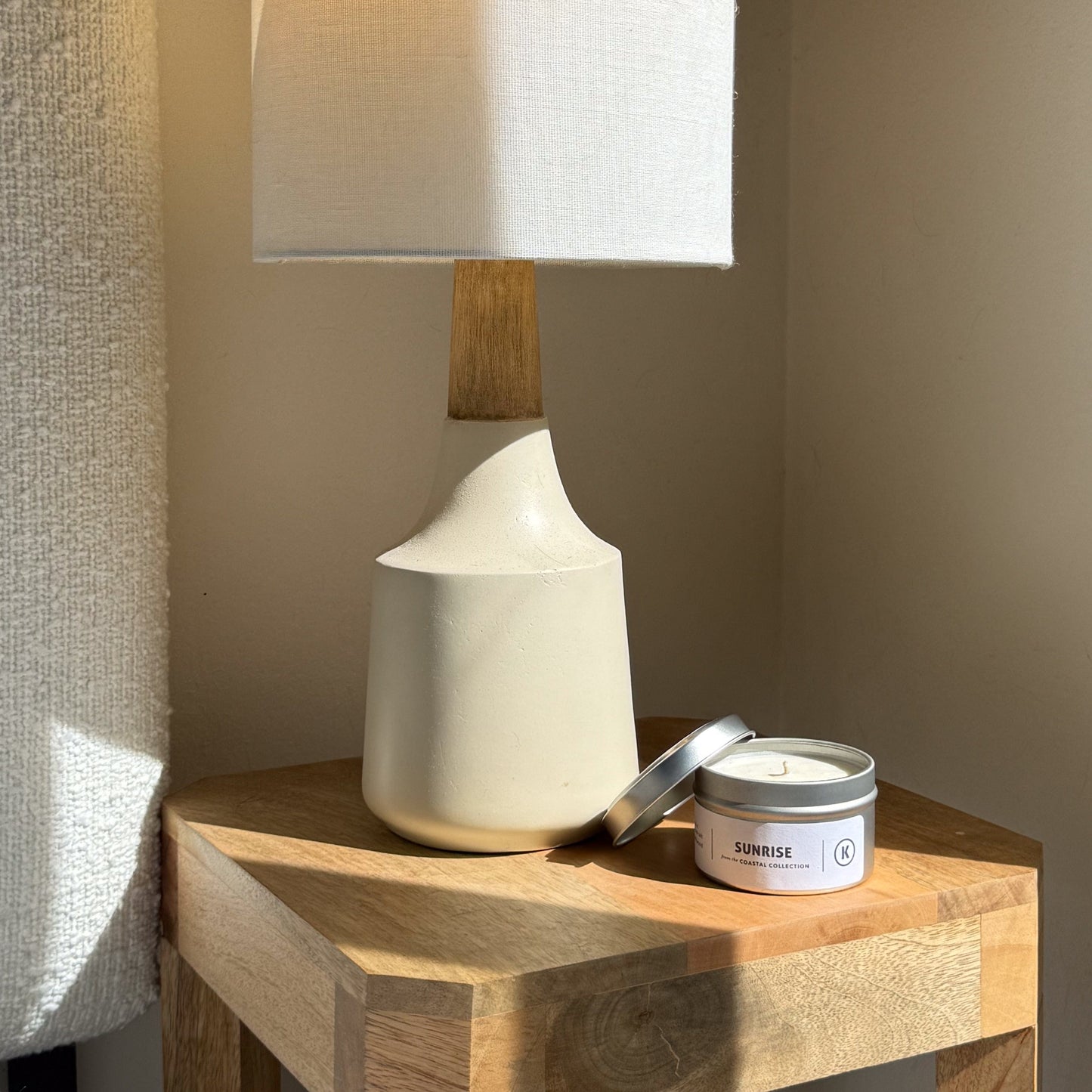 White ceramic lamp and candle on a wooden surface with a neutral background